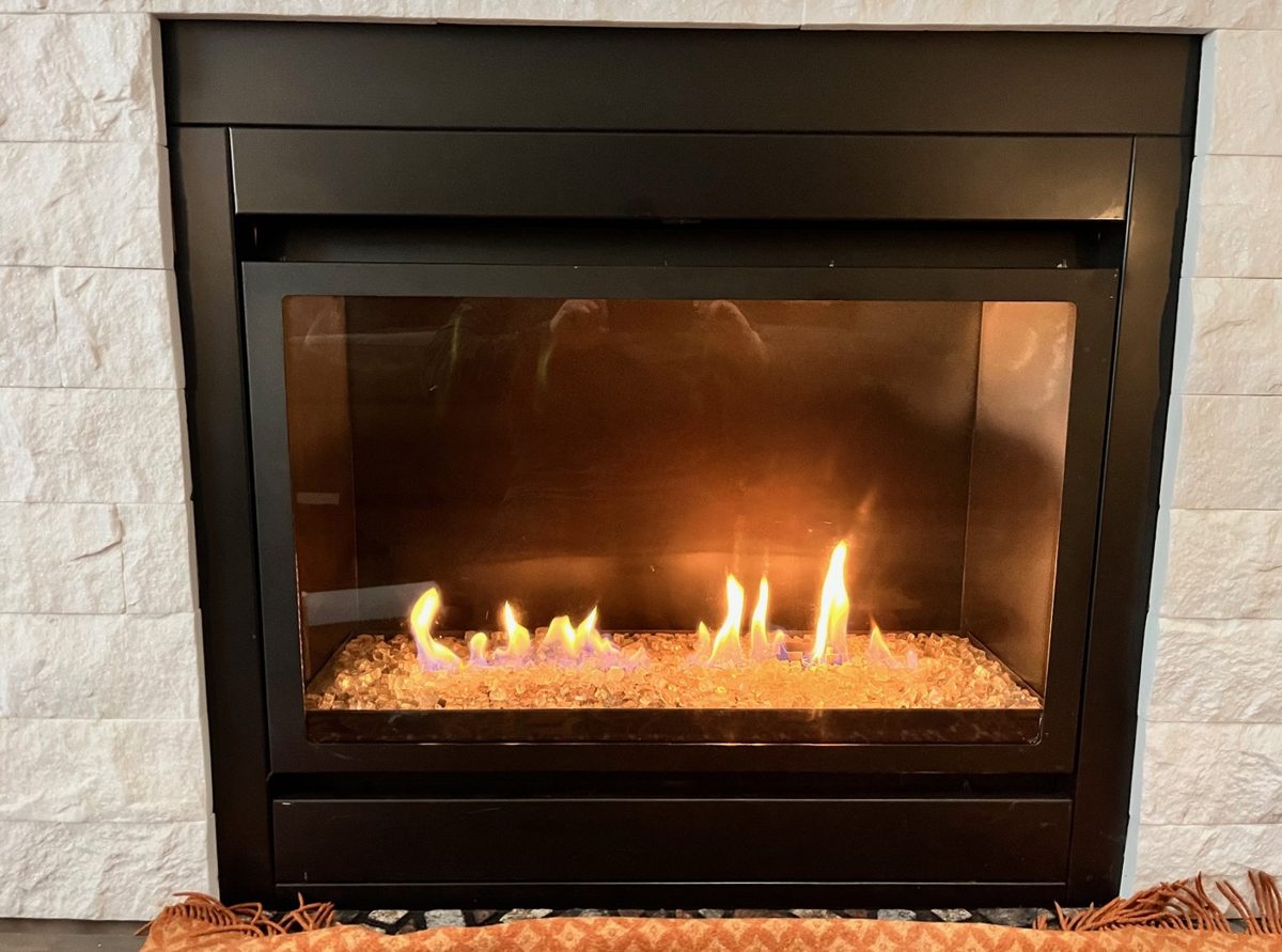 A supplied work photograph shows a black-framed fireplace, glass-effect media and visible flames within a pale stone surround